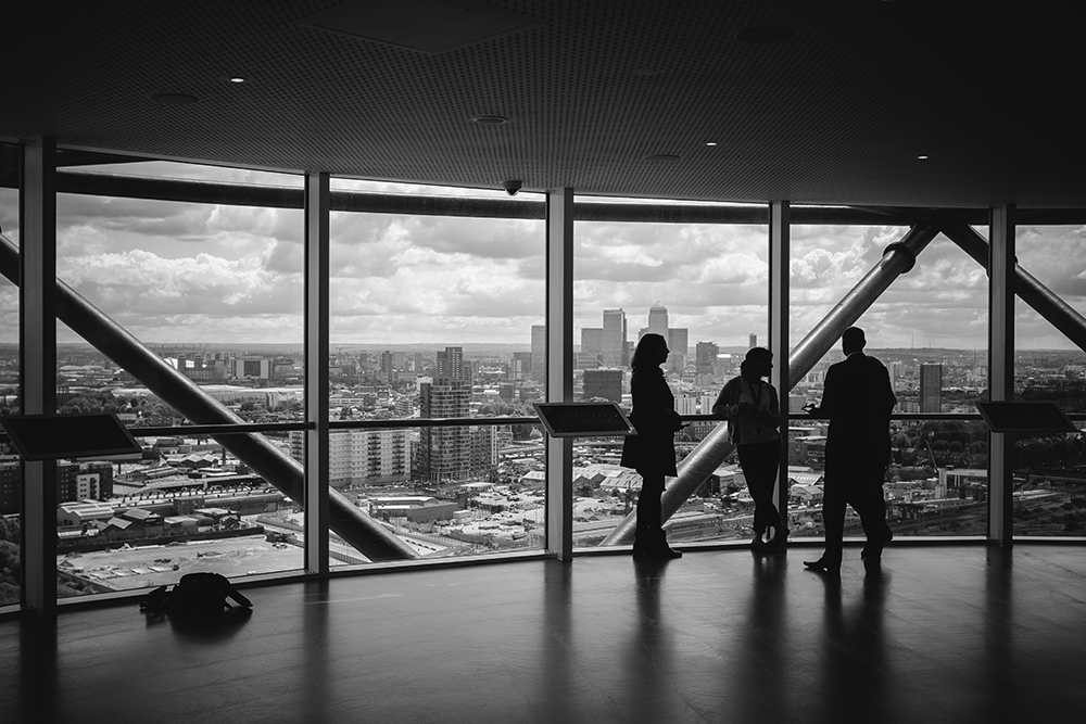 network successfully | group of professionals standing in front  of a large window overlooking the city. 